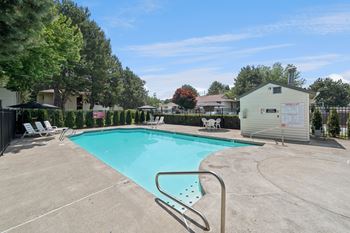 A swimming pool surrounded by a concrete patio and trees.